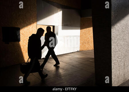 People walk past as silhouettes amongst angle, light and shadows underneath Centrepoint in central London, which is under refurbishment and in the smae are as major Crossrail construction. Stock Photo