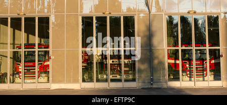 Fire trucks behind glass doors at fire station garage , Finland Stock Photo