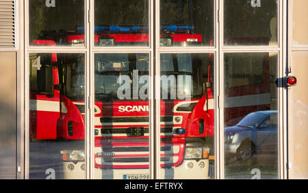 Scania fire truck behind glass doors at fire station garage , Finland Stock Photo