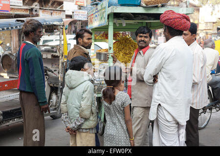 Jodhpur, Rajasthan, India. Customers by a food stall selling fried snacks in the bazaar Stock Photo