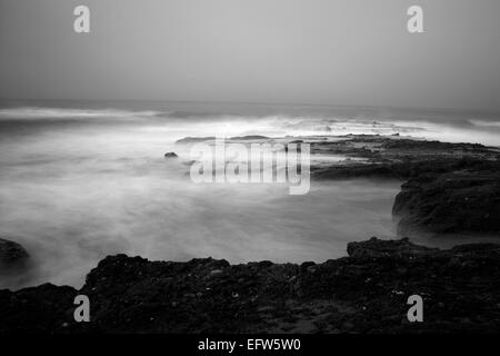 An early morning slow motion images of seawater rushing over sharp, rugged shoreline reef in Laguna Beach, California. Stock Photo