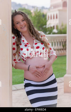 happy pregnat woman making heart shape with hands on tummy. Stock Photo