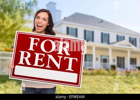 Excited Mixed Race Female Holding For Rent Sign In Front of Beautiful House. Stock Photo