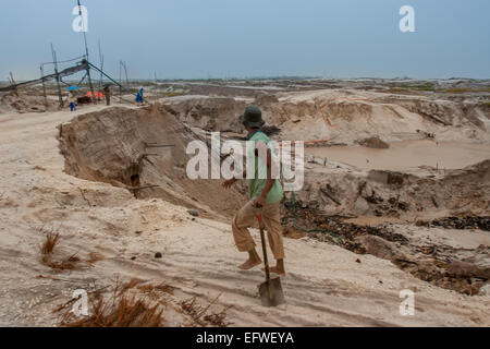 Small-scale gold miner passing through moon-like dunes in Borneo. Stock Photo