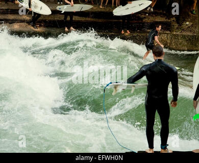Surfers practice in Englischer Garten in Munich on the artificial wave at Eisbach, small river crossing the park Stock Photo