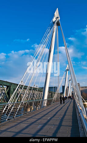 Tourists on the Hungerford Bridge over the River Thames, bright sunny day, central London, England UK Stock Photo