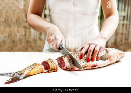 girl with a knife cut the fish into pieces of carp Stock Photo