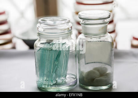 Bottles with glass pieces and swabs in a lab; Petri dishes stacked on the background Stock Photo