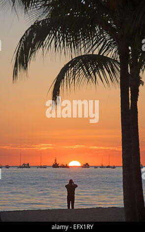 DOMINICAN REPUBLIC. A tourist photographing the rising sun at Punta Cana beach. 2015. Stock Photo