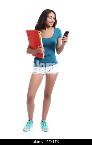 Standing teen girl holding folders and texting in a smart phone isolated on a white background Stock Photo