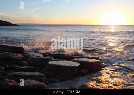 Waves breaking over rocks on Welsh beach at dusk Stock Photo