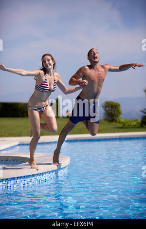 Young couple jumping in the pool on Holiday Stock Photo