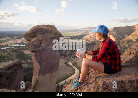 Young woman sitting gazing at view from top of Smith Rock, Oregon, USA