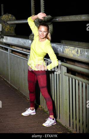 Young woman training on footbridge at night Stock Photo
