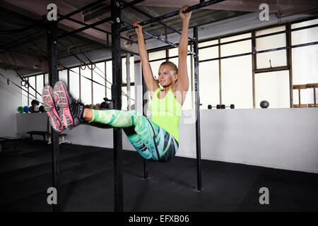 Young woman training on parallel bars in gym Stock Photo