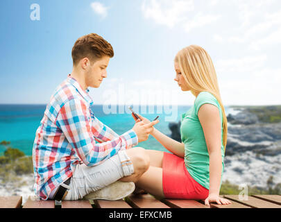 couple with smartphones sitting on bench Stock Photo