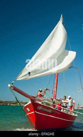 Lateen (Latin) sail boat and crew on the sea near the coast of Palau ...