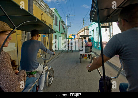 Horizontal view of bicitaxis riding through the streets in Camaguey, Cuba. Stock Photo