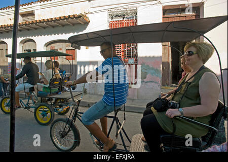 Horizontal view of bicitaxis riding through the streets in Camaguey, Cuba. Stock Photo