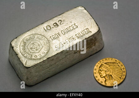 Old Poured and Stamped Silver Bullion Bar and 1911 Five Dollar United States Gold Coin Stock Photo