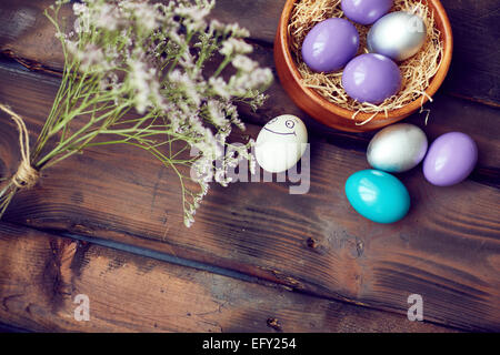 Colorful Easter eggs and dry flowers on wooden background Stock Photo
