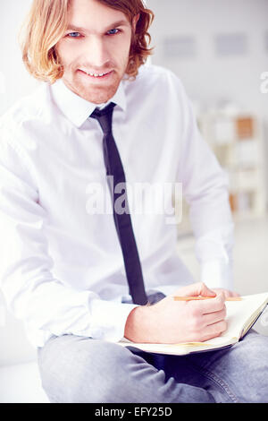 Happy businessman with notepad looking at camera Stock Photo