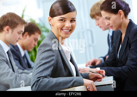 Cheerful manager sitting at workplace on background of working partners Stock Photo