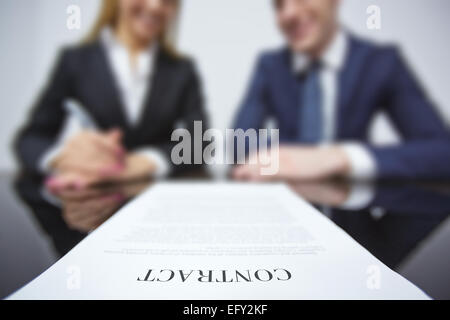 Business contract on workplace with two colleagues on background Stock Photo