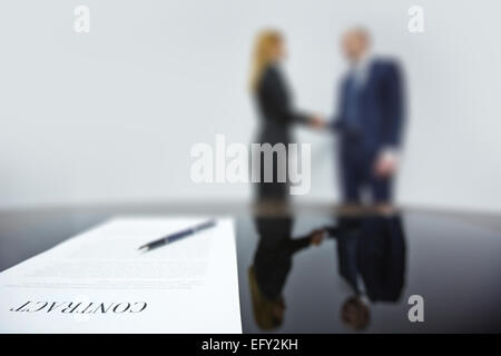 Business contract with pen on background of co-workers handshaking Stock Photo