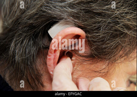 Elderly lady woman female wearing hearing aid in her ears hard of hearing Stock Photo