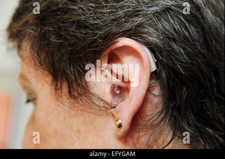 Elderly lady woman female wearing hearing aid in her ears hard of hearing Stock Photo