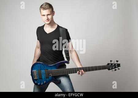 young male musician with six-string bass guitar isolated on light background Stock Photo