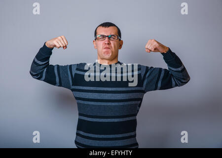 the man of European appearance brunet in sweater shows the stren Stock Photo