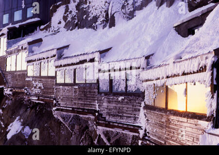 sunset colours warm up the windows covered in winter ice at the Aiguille du Midi top station, Chamonix, France Stock Photo