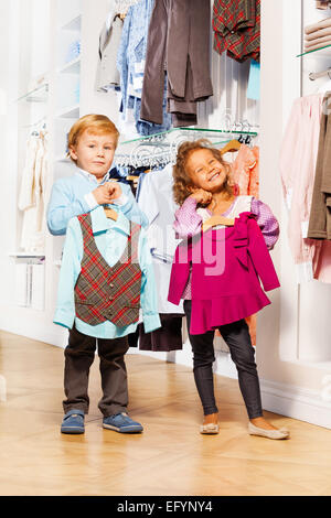 Boy fits vest and girl with sweater in store Stock Photo
