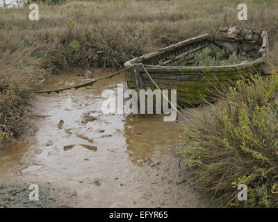 Hull of an old decaying wooden rowing fishing boat with holes in on a ...