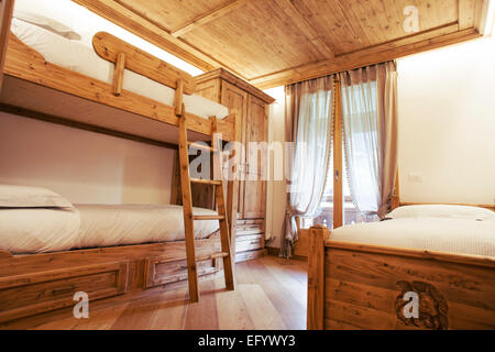 Triple room with single and bunk beds in a children's bedroom. Alpine style Stock Photo