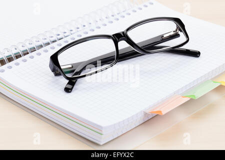 Office table with glasses over blank notepad Stock Photo