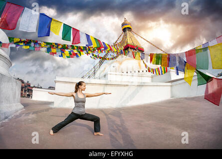 Woman doing yoga warrior pose at Bodnath stupa, Kathmandu, Nepal Stock Photo