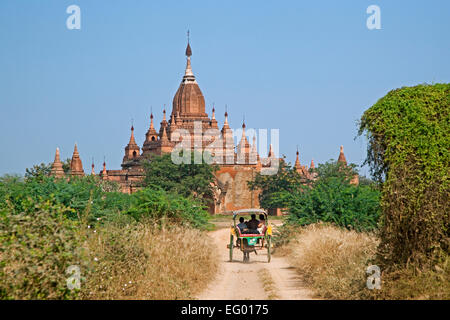 Tourists in horse drawn carriage visiting ancient Buddhist temple / pagoda in the Bagan Plains, Mandalay Region, Myanmar / Burma Stock Photo