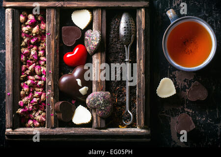 Set of dry tea, heart from tea and chocolate and cup of tea. Top view. Stock Photo