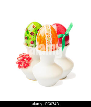 three colored easter eggs in cup with ribbon on white background Stock Photo