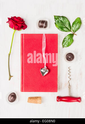 Love story composing with book, heart, red rose, chocolate and corkscrew on white background, top view Stock Photo