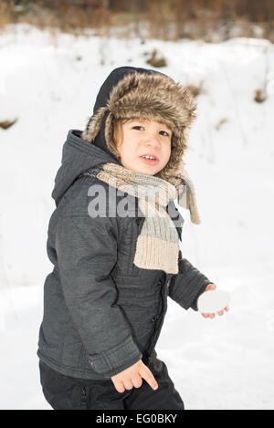 Beauty toddler boy walking  in the snow holding snowball Stock Photo