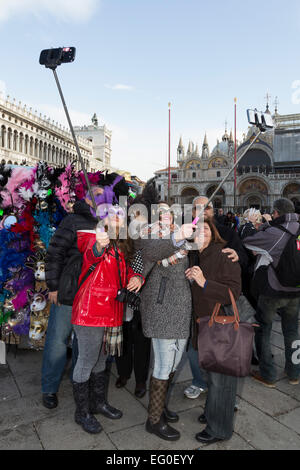 Venice, Italy. People dress in costumes and wear masks as they celebrate the 2015 Carnival in Venice, Italy. People take selfies with selfie sticks. Stock Photo