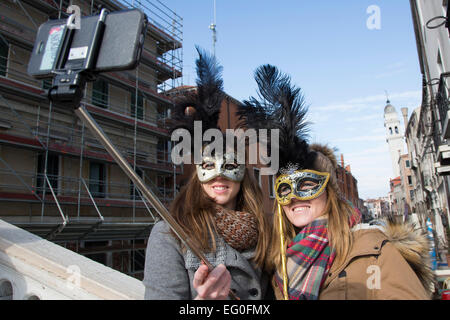 Venice, Italy. People dress in costumes and wear masks as they celebrate the 2015 Carnival in Venice, Italy. Two women take a selfie with a selfie stick. Stock Photo