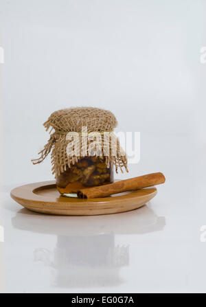 jar with walnuts jam and cinnamon on a small wooden plate Stock Photo