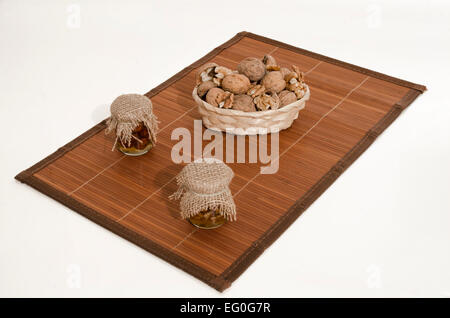 Walnuts in basket and nuts jam in small jars on wood Stock Photo