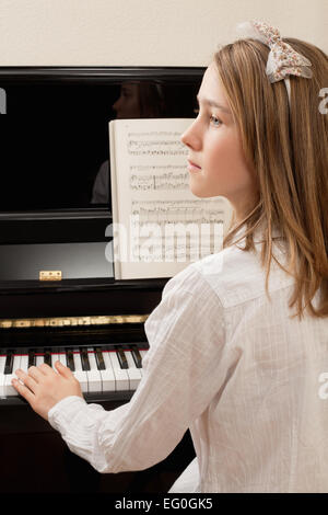 Photo of a young girl playing the piano at home. Stock Photo