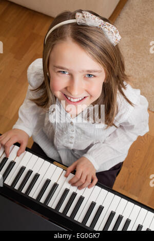 Photo of a happy young girl playing the piano at home. Stock Photo